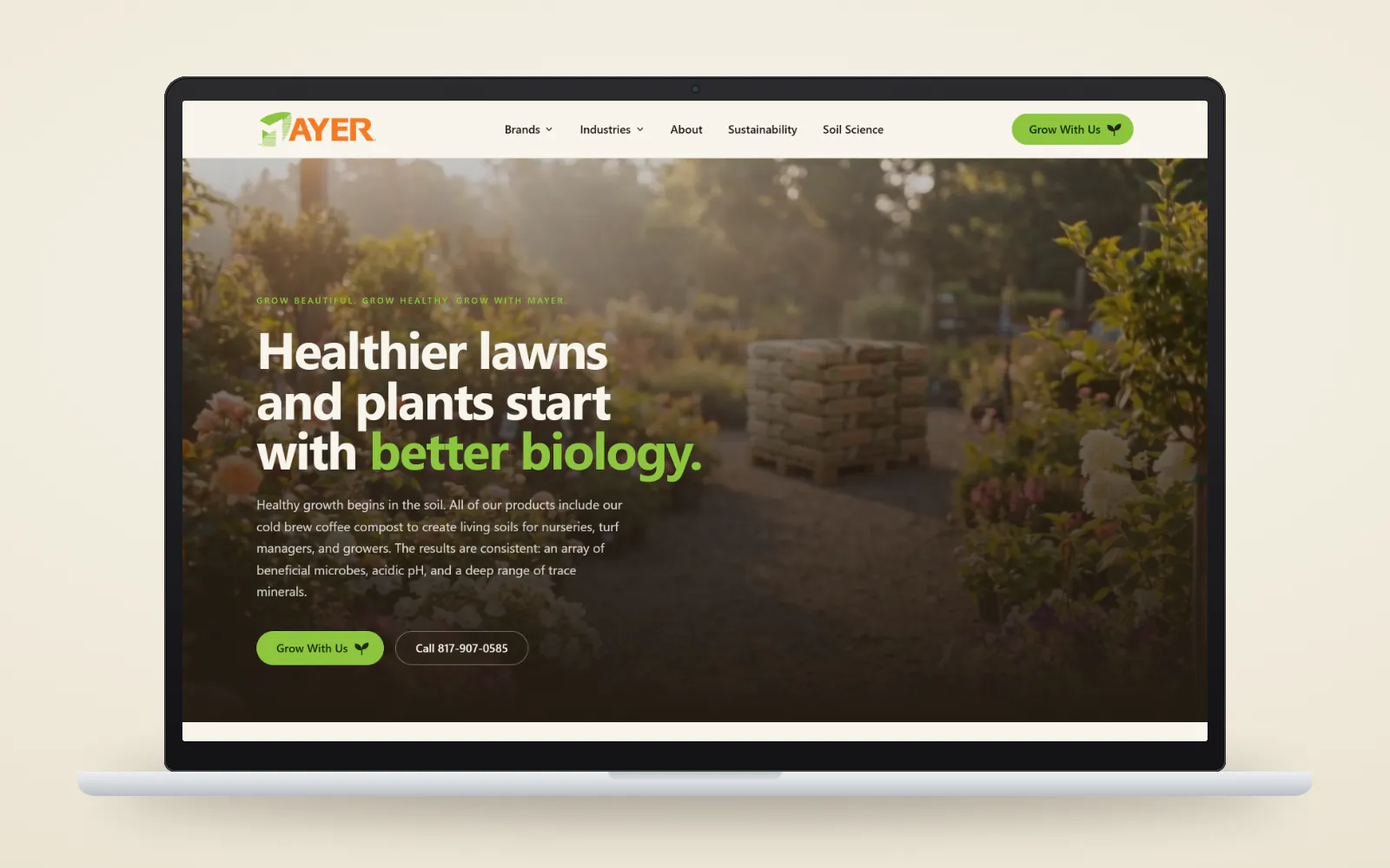 The new mayermaterials.com homepage on a laptop, with the eyebrow Grow Beautiful. Grow Healthy. Grow with Mayer., the headline Healthier lawns and plants start with better biology., Grow With Us and Call 817-907-0585 buttons, and a video frame of a pallet of Mayer bags in a sunlit garden.